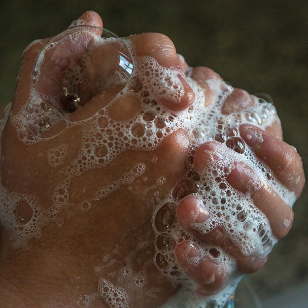 Hands being washed with soap and water bubbles, demonstrating proper hygiene practices.