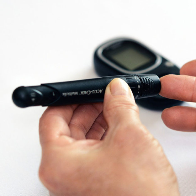 Person holding blood glucose meter and lancing device for diabetes testing.