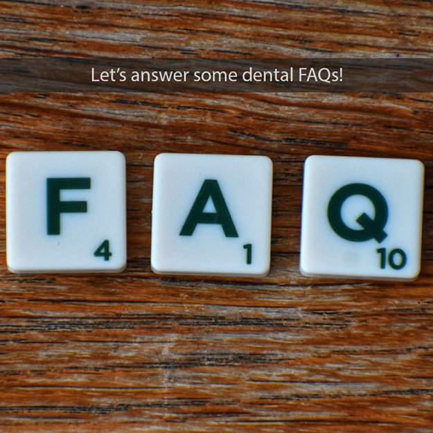 Scrabble tiles spelling FAQ on wooden surface for dental frequently asked questions.