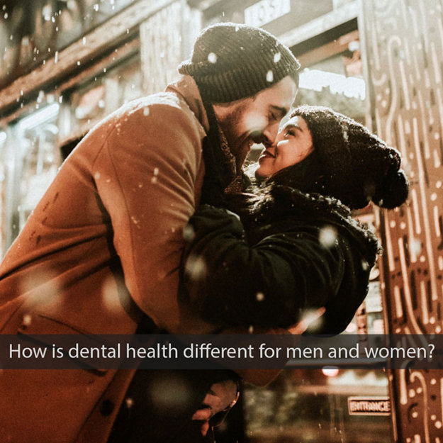Couple kissing outdoors in winter setting with snow falling around them.