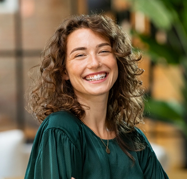 Smiling young woman with curly hair representing cosmetic dentistry services at Dentistry of Old Town Scottsdale