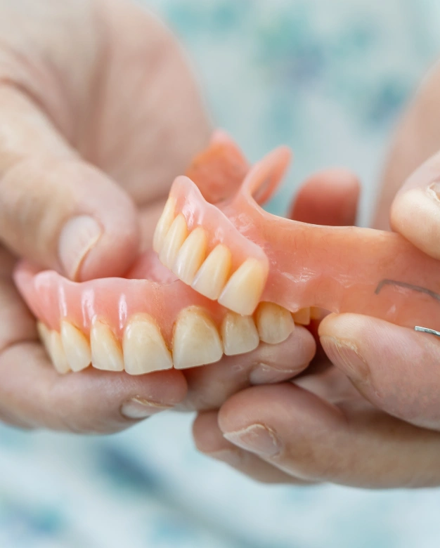 Dental professional showing a patient a denture model representing denture and partial denture services in Scottsdale