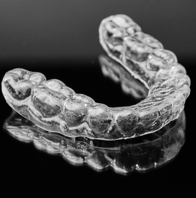 Clear occlusal night guard on a dark background representing custom night guard services at Dentistry of Old Town Scottsdale