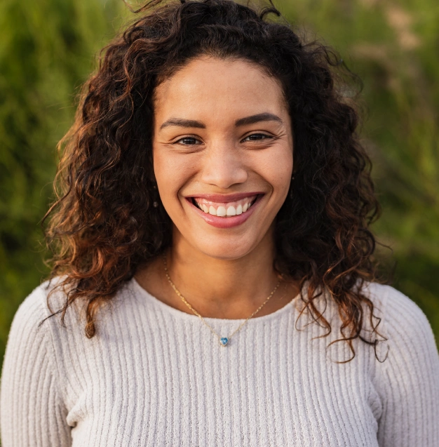 Smiling young woman with curly hair representing prosthodontic dental services at Dentistry of Old Town Scottsdale