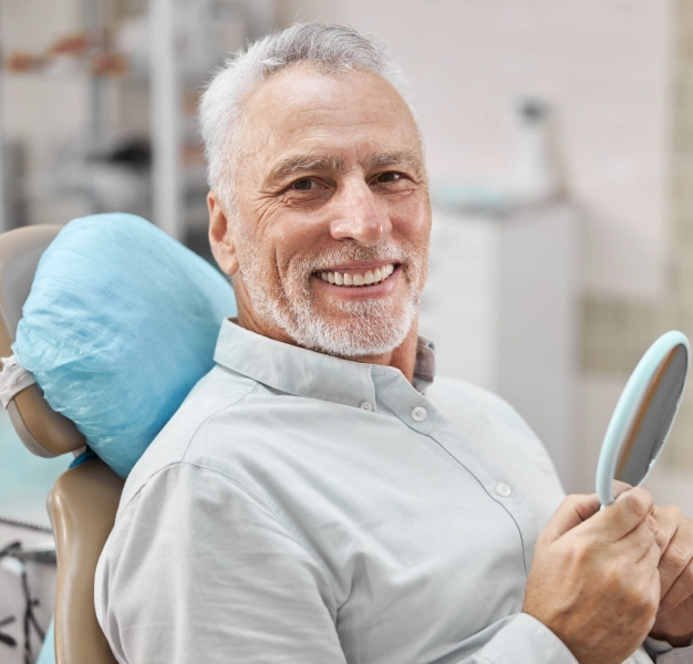 Older man smiling in a dental office representing root canal retreatment services at Dentistry of Old Town Scottsdale