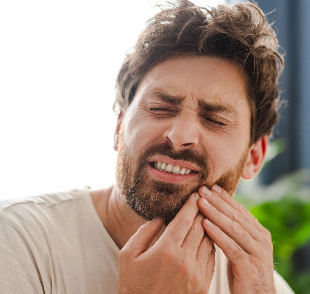 Man grimacing and holding his jaw representing traumatic dental injury treatment at Dentistry of Old Town Scottsdale