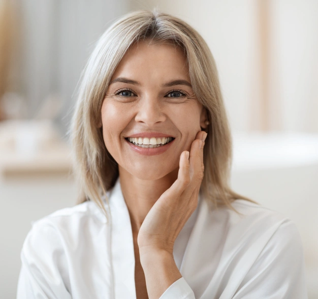 Smiling woman touching her face representing cosmetic wrinkle treatment services available at Dentistry of Old Town Scottsdale