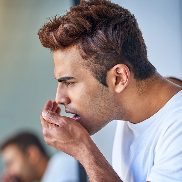 Young man covering his mouth representing oral malodor causes and treatment at Dentistry of Old Town Scottsdale