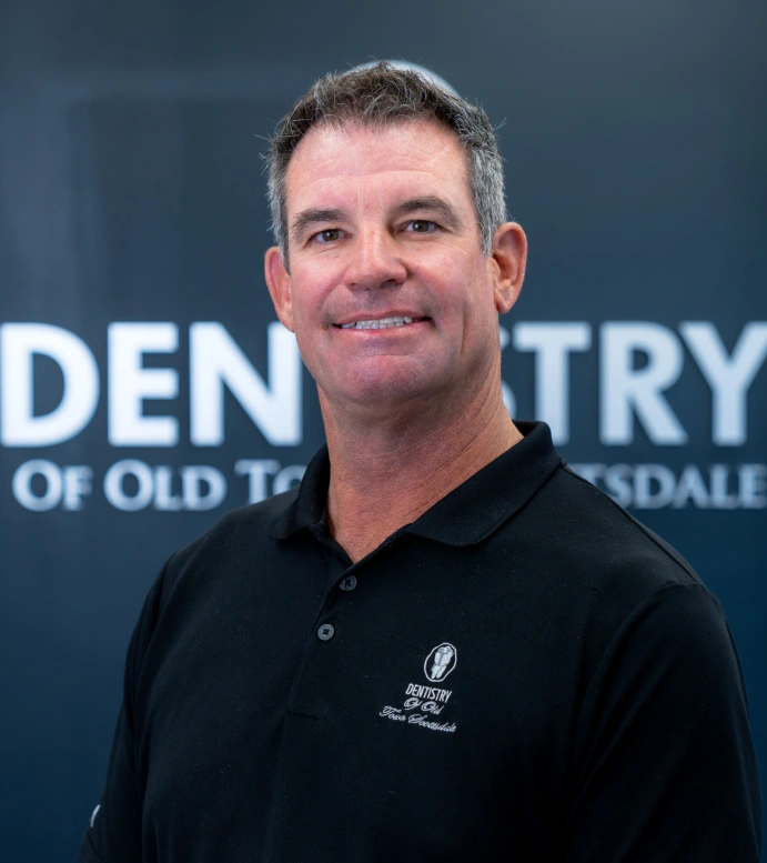 Dr. Bradley Brittain smiling in front of the Dentistry of Old Town Scottsdale sign used on the homepage