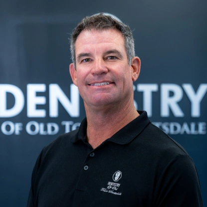 Dr. Bradley Brittain smiling in front of the Dentistry of Old Town Scottsdale sign in a professional photo