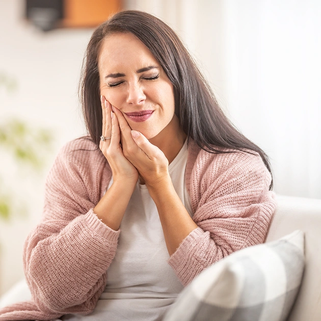 Young woman holding her cheek in discomfort representing orthodontic emergency care at Dentistry of Old Town Scottsdale