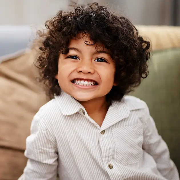 Happy young child with curly dark hair smiling at pediatric dental office in Scottsdale.