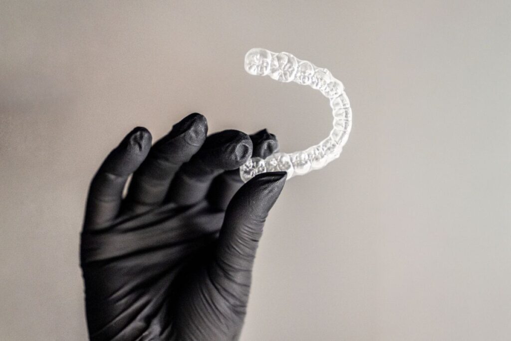 Clear aligner tray held by a dental professional as an alternative to fix uneven teeth without braces