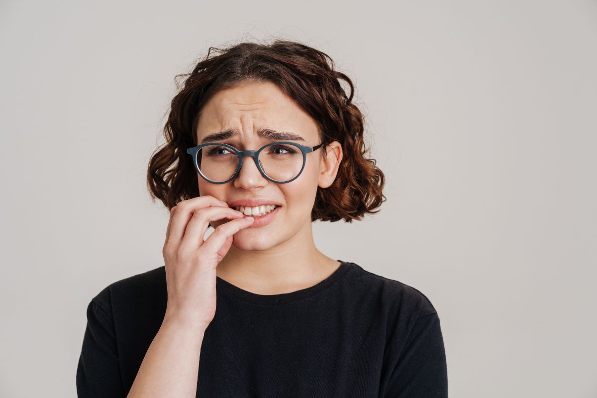 Anxious woman biting her nails, a habit that can chip teeth or cause a lost filling